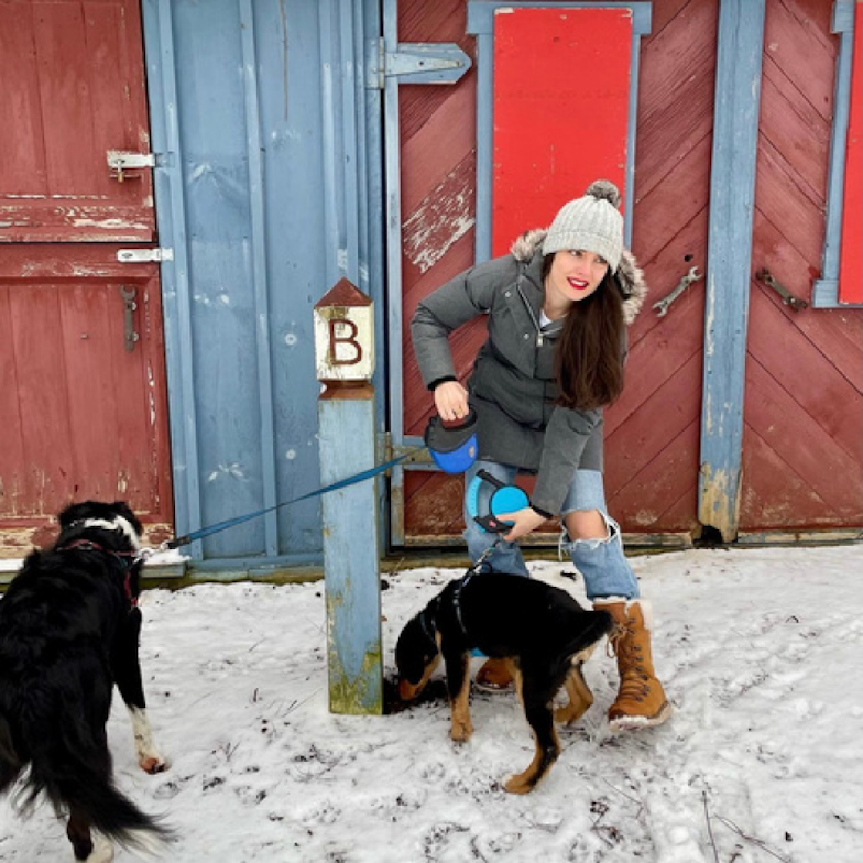 woman outside in the snow with two dogs