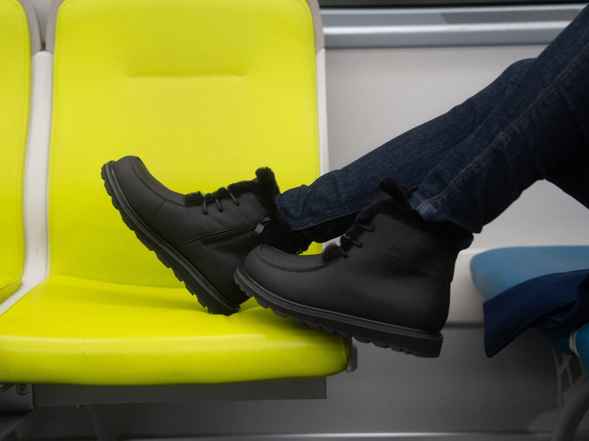 LEORA in All Black, feet up on a transit seat