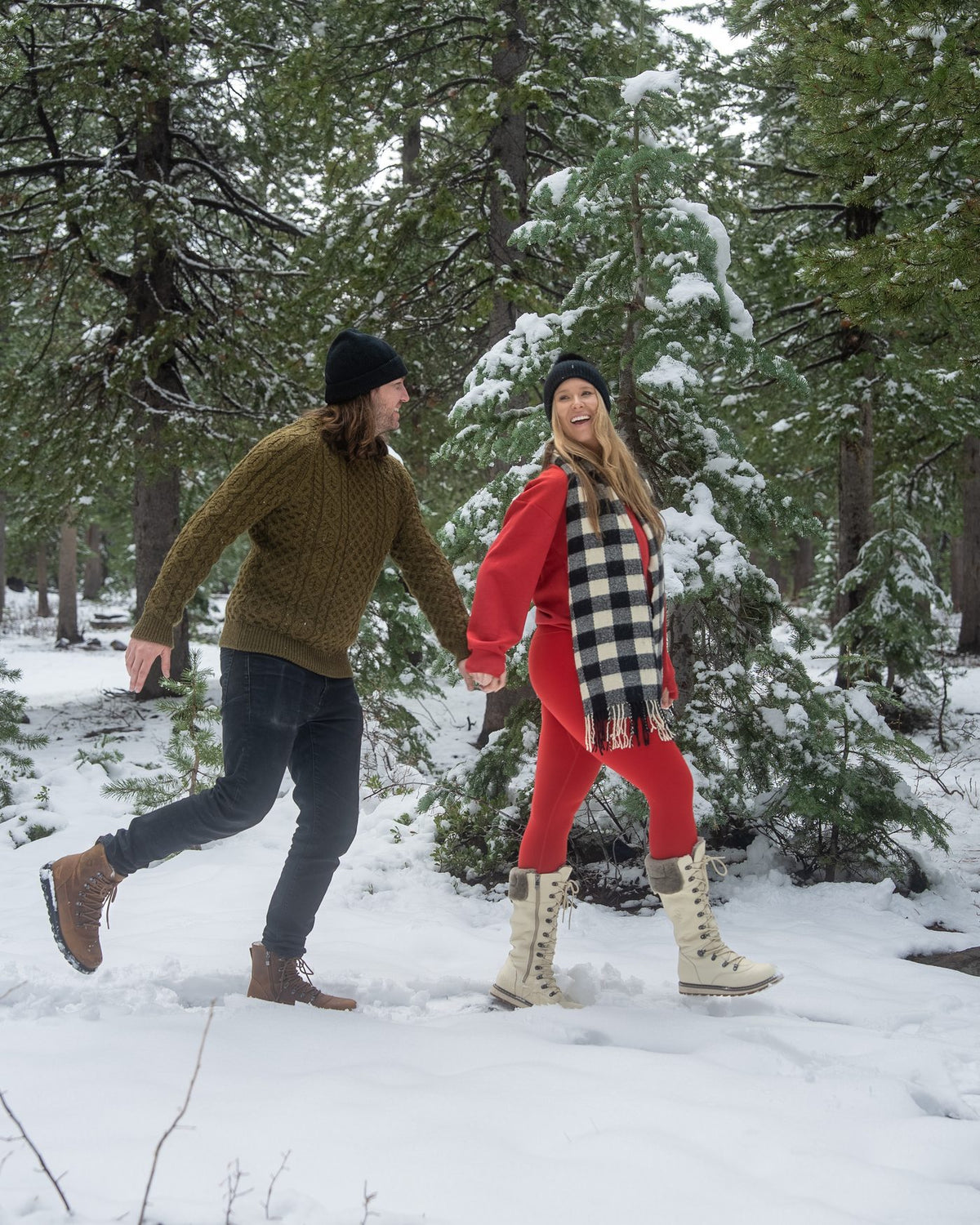 A couple walking through a snowy forest, her in DALHOUSIE Pale Ale White